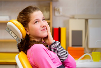 Una chica joven con dolor de muelas en el dentista.