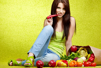 Una mujer joven con una bolsa llena de frutas y verduras.