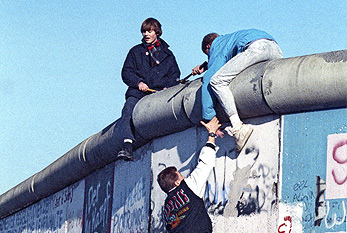 Los hombres jóvenes de escalada del muro de Berlín en noviembre de 1989.