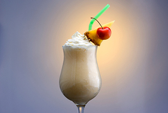 Una Piña Colada decorado con una rodaja de piña y una cereza.