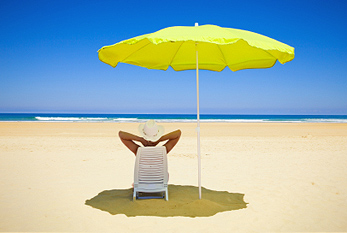Mujer que se reclina bajo un parasol de playa para protegerse de la luz solar.