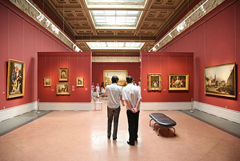 Los visitantes en un museo de arte con cuadros en las paredes.