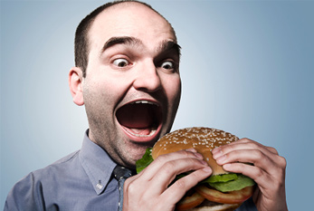 Hombre comiendo hamburguesa en el Día Internacional Sin Dietas: ninguna dieta, ninguna problema!