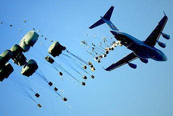 Un avión lanzamientos paletas de agua y alimentos a través de una zona de desastre.