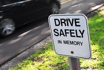 Una muestra conmemorativa en el borde de la carretera con el "Maneje con cuidado" inscripción.