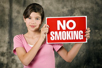 Una niña sostiene una señal de prohibido fumar.