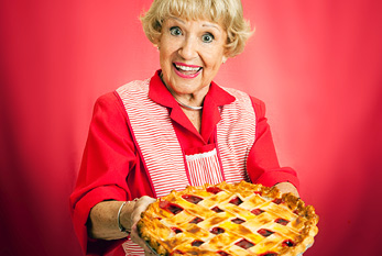 Abuela sosteniendo un pastel de celosía superior cereza recién horneado.